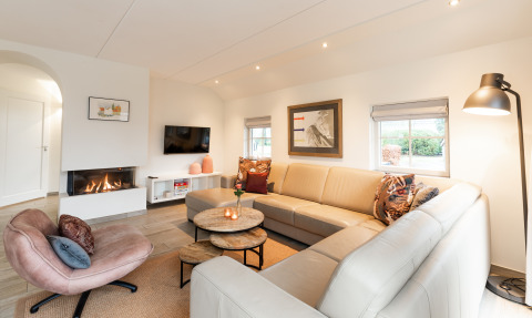 Moderne woonkamer in Wellness Lodge XXL te Hof van Salland, Nederland, met open haard en hoekzetel.