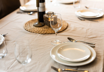 Mesa con platos, cubiertos y copa de vino en Wellness Lodge XXL, Hof van Salland, Países Bajos.