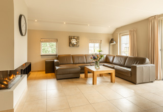 Heldere, moderne woonkamer met lederen zetel en open haard in Wellness Lodge XXL bij Hof van Salland, Nederland.