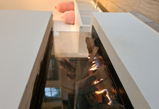 Moderne haard met glas en decoratieve houtblokken in Wellness Lodge XXL bij Hof van Salland, Nederland.