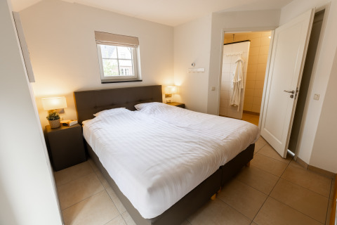 Slaapkamer in Wellness Lodge XXL bij Hof van Salland, Nederland, met tweepersoonsbed en open badkamer.