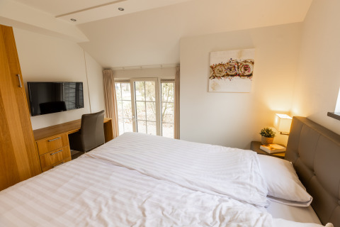 Slaapkamer in Wellness Lodge XXL van Hof van Salland, Nederland, met groot bed, televisie en bureau.