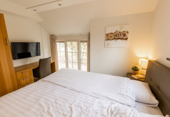 Dormitorio en Wellness Lodge XXL en Hof van Salland, Países Bajos, con cama grande, escritorio y televisión.