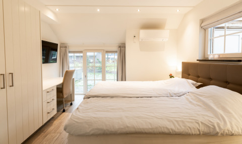 Lichte, moderne slaapkamer in Wellness Lodge XXL, Hof van Salland, Nederland, met tweepersoonsbed en bureau.