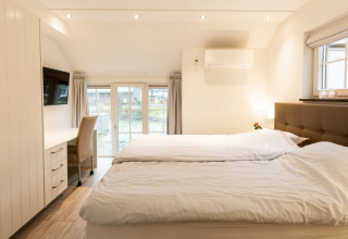 Lichte, moderne slaapkamer in Wellness Lodge XXL, Hof van Salland, Nederland, met tweepersoonsbed en bureau.