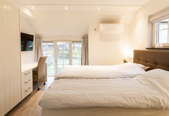 Dormitorio luminoso y moderno en Wellness Lodge XXL, Hof van Salland, Países Bajos, con cama doble y escritorio.
