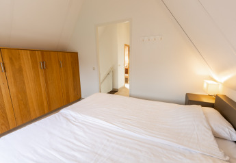 Dormitorio con cama doble, armario de madera y lámpara en Wellness Lodge XXL de Hof van Salland, Países Bajos.