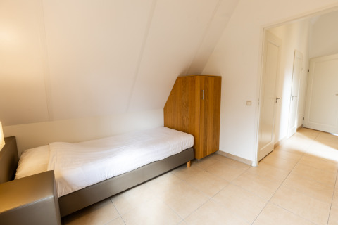 Lichte eenpersoonskamer met een bed en kleerkast in Wellness Lodge XXL bij Hof van Salland, Nederland.