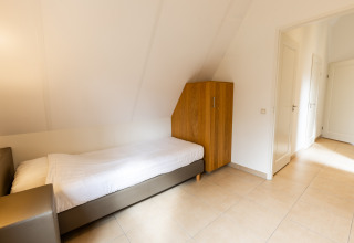 Lichte eenpersoonskamer met een bed en kleerkast in Wellness Lodge XXL bij Hof van Salland, Nederland.