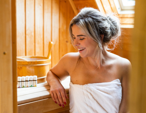 Vrouw geniet in Wellness Lodge XXL bij Hof van Salland, Nederland, gewikkeld in een witte handdoek in de sauna.