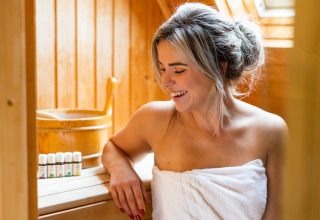 Vrouw geniet in Wellness Lodge XXL bij Hof van Salland, Nederland, gewikkeld in een witte handdoek in de sauna.
