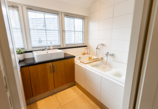 Moderne badkamer met bad, wastafel en grote ramen in Wellness Lodge XXL, Hof van Salland, Nederland.
