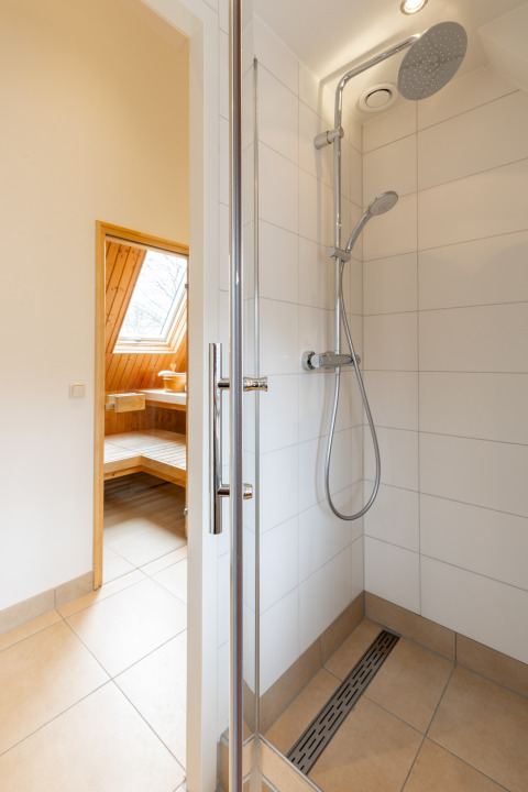Moderne douche met glazen deur en regendouche, zicht op sauna in Wellness Lodge XXL, Hof van Salland.