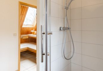 Ducha moderna con puerta de cristal y cabezal tipo lluvia, vista a la sauna en Wellness Lodge XXL, Hof van Salland.