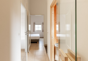 Pasillo luminoso hacia dormitorio y baño en Wellness Lodge XXL de Hof van Salland, Países Bajos.