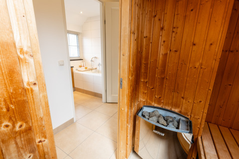 Sauna met houten afwerking en Harvia-verwarming naast een badkamer in Wellness Lodge XXL, Hof van Salland.