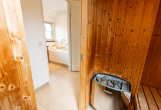 Sauna met houten afwerking en Harvia-verwarming naast een badkamer in Wellness Lodge XXL, Hof van Salland.