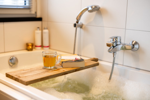 Ontspannend badmoment met thee, boek en houten plank bij Wellness Lodge XXL, Hof van Salland, Nederland.