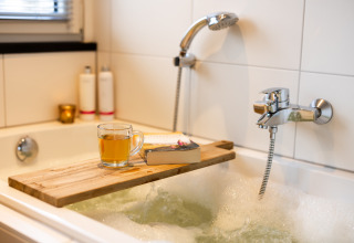 Ontspannend badmoment met thee, boek en houten plank bij Wellness Lodge XXL, Hof van Salland, Nederland.