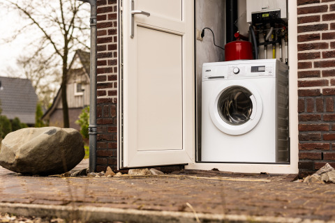 Een wasmachine staat in een kleine kamer met open deur bij Wellness Lodge XXL, Hof van Salland, Nederland.