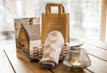 Cadeau de bienvenue, brochure, serviettes et bougie sur une table à la Wellness Lodge XL, Hof van Salland.