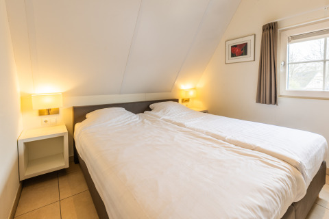 Schlafzimmer in der Wellness Lodge XL im Hof van Salland, Niederlande, mit zwei Betten und Fenstern.