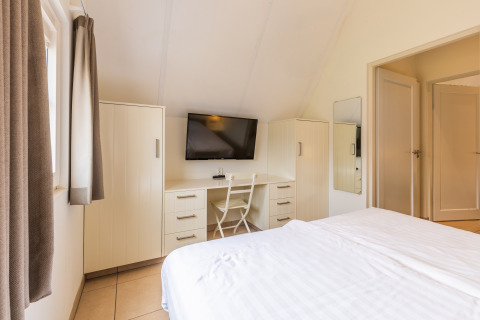 Dormitorio luminoso en Wellness Lodge XL, Hof van Salland, Países Bajos, con TV, escritorio y cama.