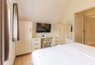 Helles Schlafzimmer in der Wellness Lodge XL im Hof van Salland, Niederlande, mit TV und Schreibtisch.