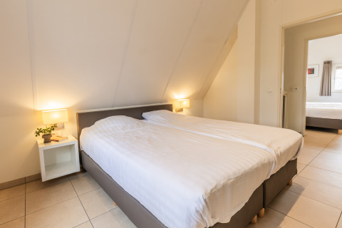 Dormitorio en la Wellness Lodge XL en Hof van Salland, Países Bajos, con cama doble y mesitas.