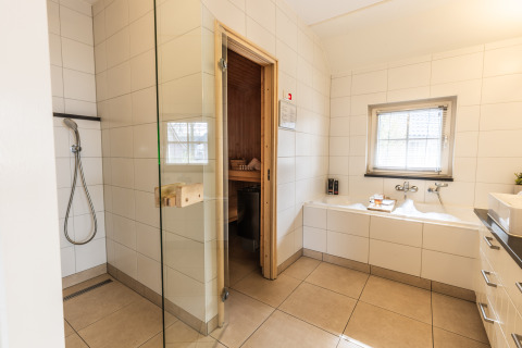 Modernes Bad mit Dusche, Badewanne und Sauna in der Wellness Lodge XL, Hof van Salland, Niederlande.