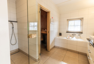 Modernes Bad mit Dusche, Badewanne und Sauna in der Wellness Lodge XL, Hof van Salland, Niederlande.