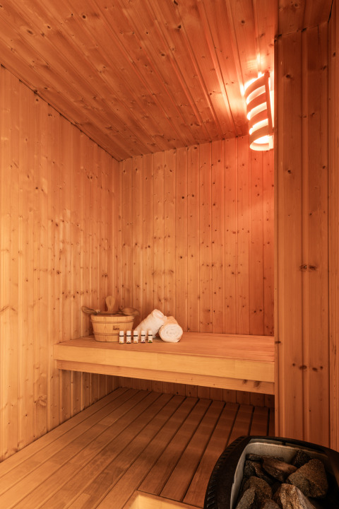 Sauna moderna de madera con iluminación suave, toallas y aceites, en Hof van Salland, Países Bajos.