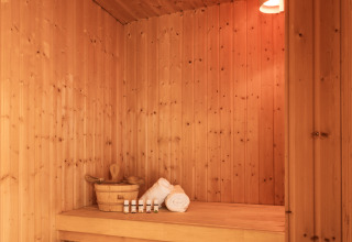 Sauna moderna de madera con iluminación suave, toallas y aceites, en Hof van Salland, Países Bajos.