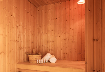 Sauna moderne en bois avec lumière douce, serviettes et huiles essentielles, à Hof van Salland, Pays-Bas.
