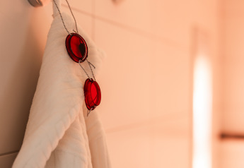 Un peignoir blanc avec des lunettes rouges est suspendu à un crochet au Wellness Lodge XL à Hof van Salland, Pays-Bas.