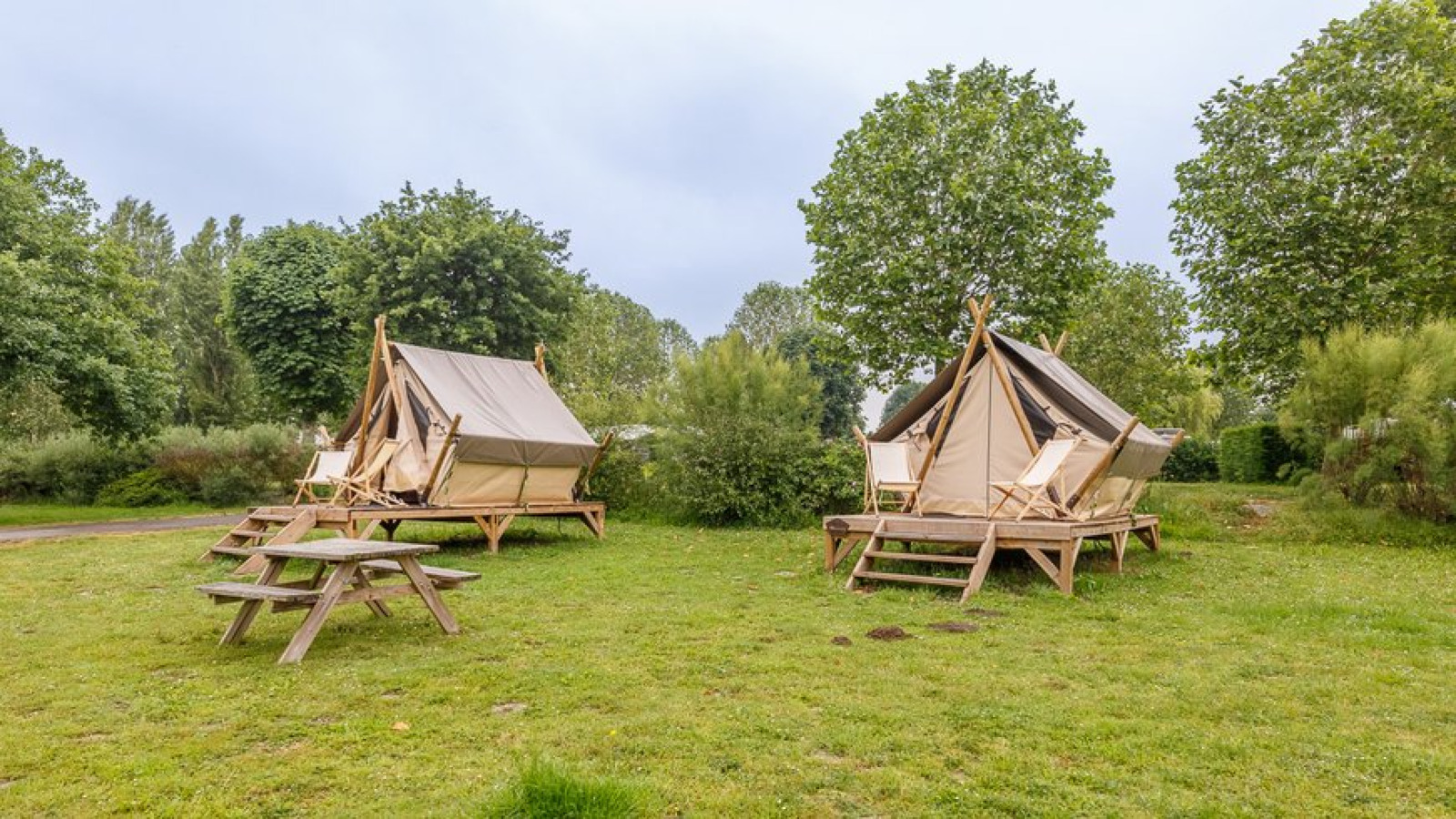 Twee Bivouac safaritenten op Camping Seasonova Lac de Bournazel, Frankrijk, tussen gras en bomen.