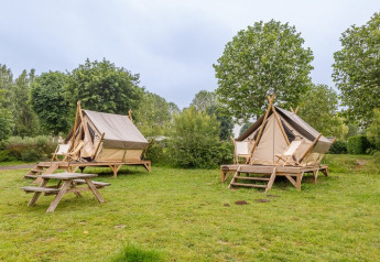 Two Bivouac safari tents at Campsite Seasonova Lac de Bournazel, France, set among grass and trees.