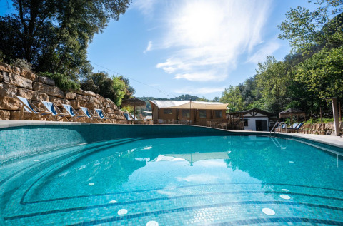 Buitenzwembad met ligstoelen bij Can Bora Lodges vakantiepark in Catalonië, Spanje, te midden van groen.