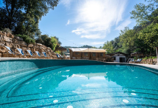 Buitenzwembad met ligstoelen bij Can Bora Lodges vakantiepark in Catalonië, Spanje, te midden van groen.