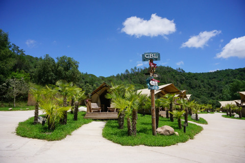 Can Bora Lodges vakantiepark in Catalonië, Spanje, met tentlodges, palmbomen en heuvelachtig landschap.