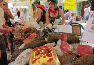 Marktkraam bij Domaine Les 2 Soleils in de Provence met lokale vleeswaren en drukte bij de verkoper.
