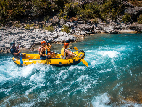 Vier mensen peddelen in een gele raft over een wilde rivier bij Serres in de Provence-Alpes-Côte d’Azur, Frankrijk.
