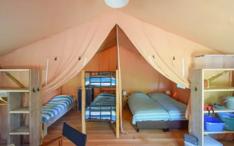 Interieur van een safaritent bij Domaine Les 2 Soleils in Frankrijk met bedden, rekken en houten inrichting.