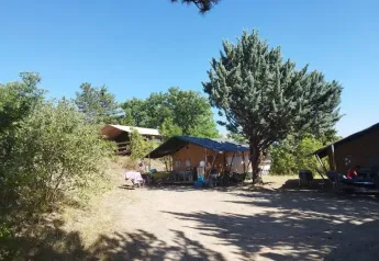 Tienda safari en Domaine Les 2 Soleils en Francia, rodeada de árboles y cielo azul despejado.