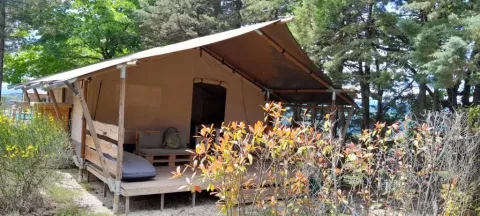 Safaritent Lodgetent met badkamer bij Camping Luna del Monte in Italië, omringd door bomen en struiken.
