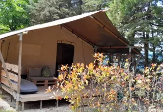 Safaritent Lodgetent met badkamer bij Camping Luna del Monte in Italië, omringd door bomen en struiken.