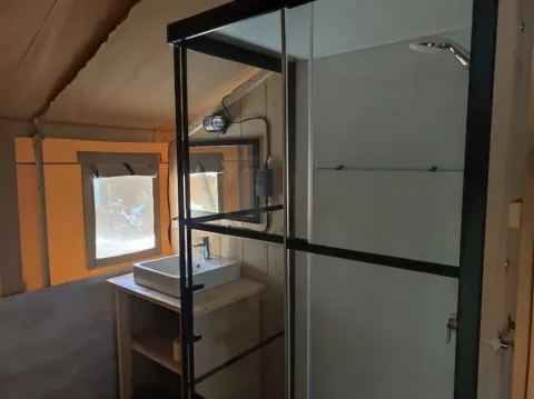 Interieur van Lodgetent met badkamer bij Camping Luna del Monte, Italië, met wastafel en douche.