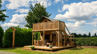 Safari tent Glampingtent 2p met houten terras, balkon en zithoek buiten in een groene omgeving.