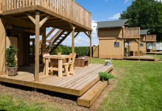 Outdoor view of Glampingtent 2p safari tent with wooden deck and seating at Campsite Mareveld, Netherlands.