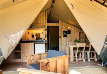 Binnenkant van een safaritent op Camping Mareveld in Nederland met een keukenblok en houten meubilair.
